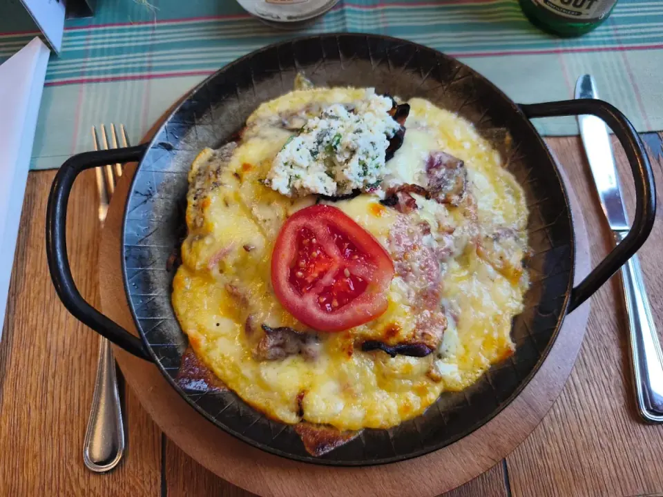 Überbackene Rösti in der Pfanne mit Bibeleskäse und Tomate